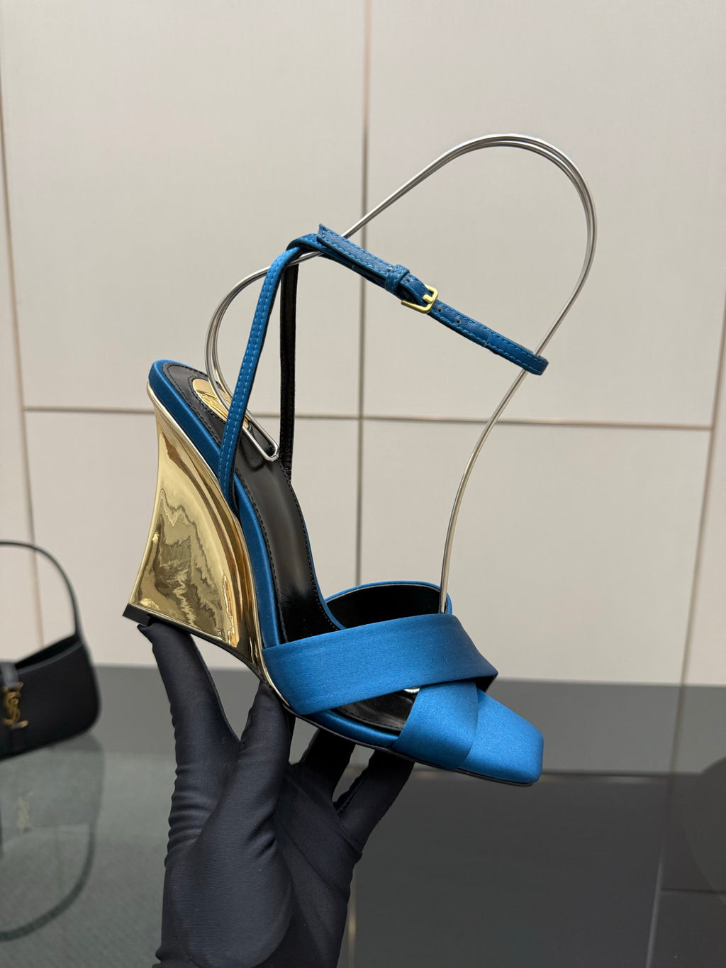 Side view of blue strappy high-heel sandals with gold wedge-heel detail