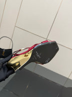 Underside of women's heeled sandal with black sole and gold heel base