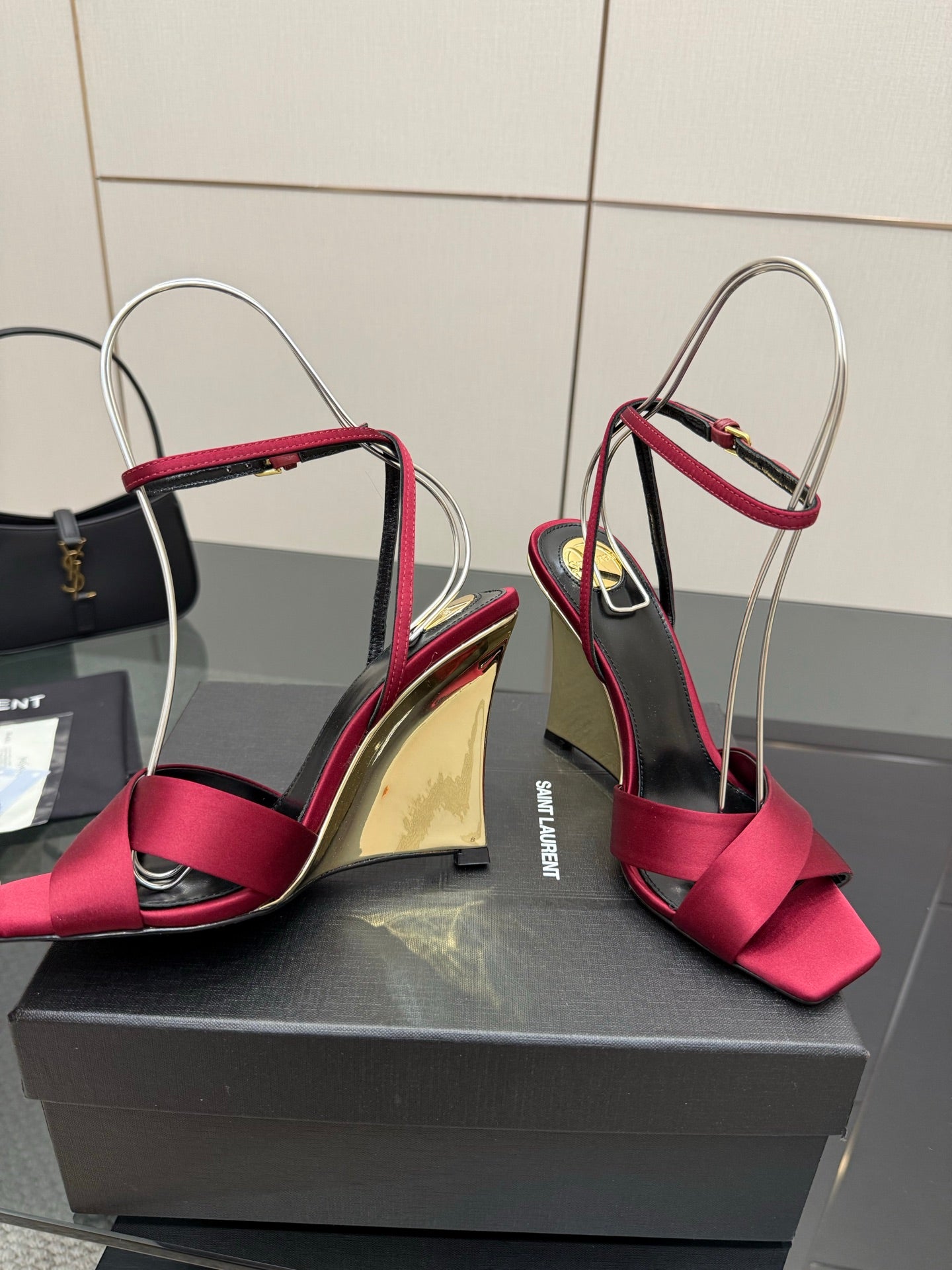 Pair of women's heeled sandals with pink bow straps and mirrored gold heel on display box