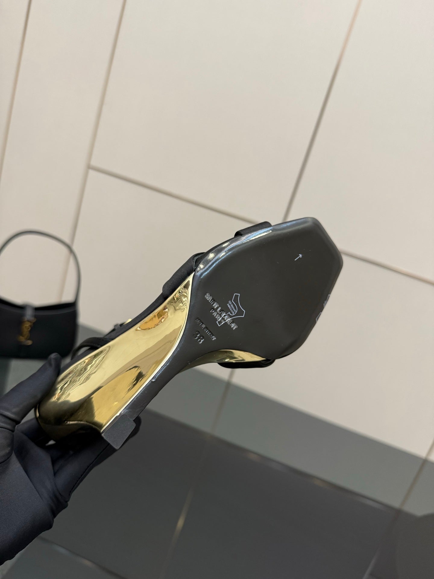 Black wedge sandal close-up of heel and gold-printed sole