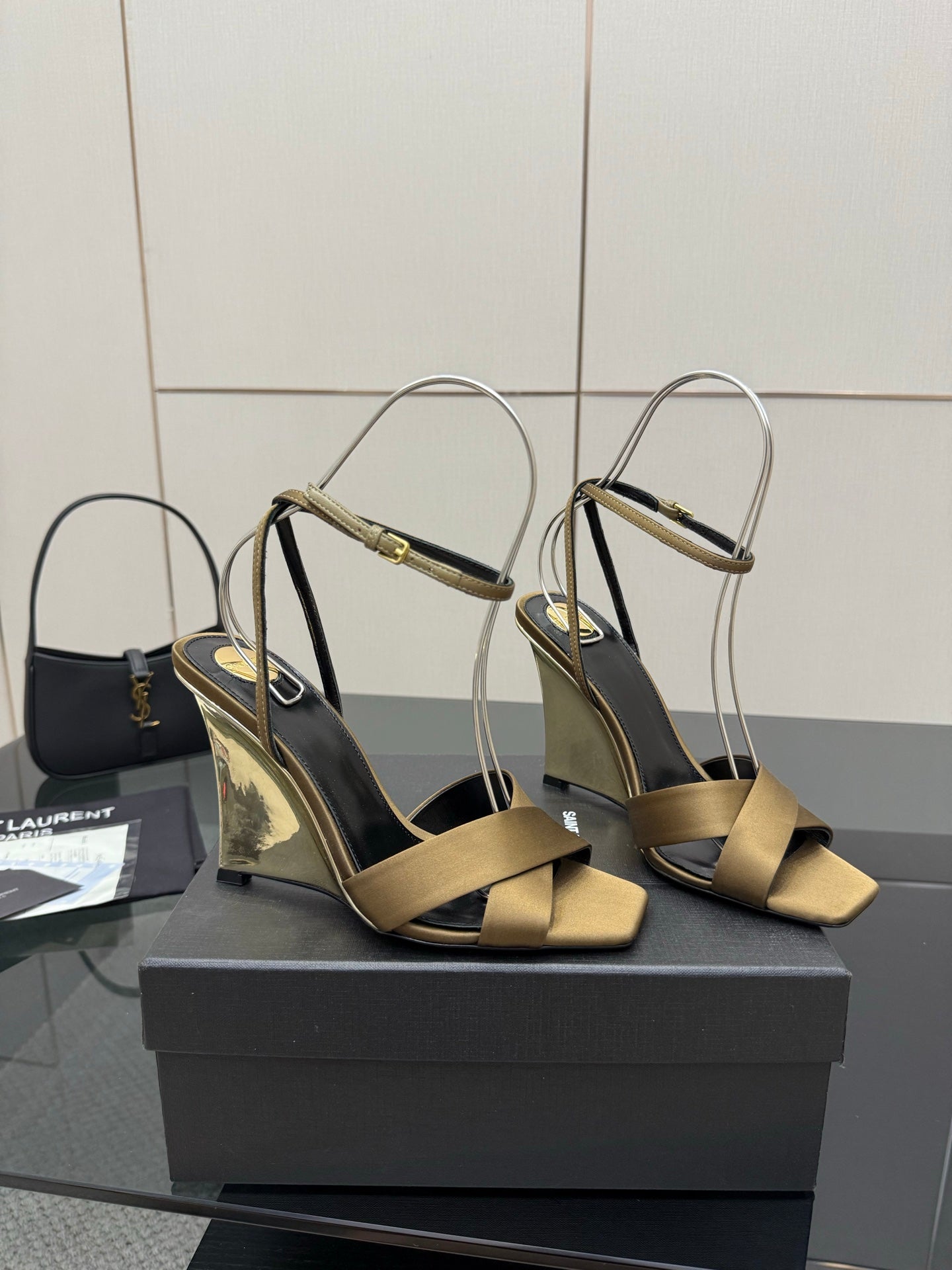Pair of gold open-toe heeled sandals with silver ankle straps and black footbed
