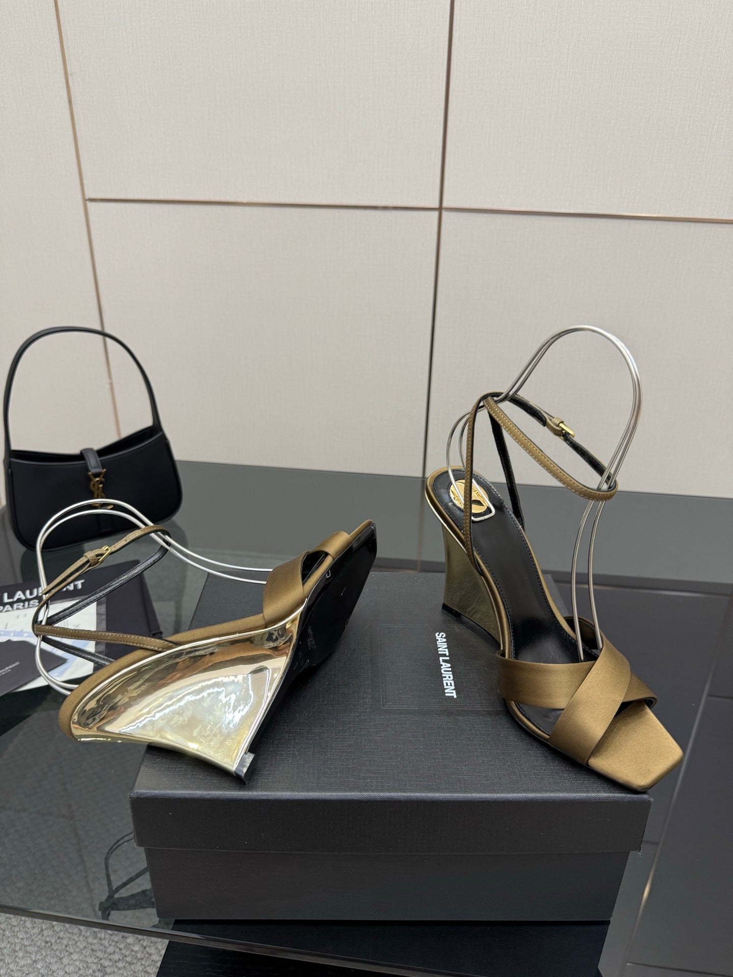 Gold open-toe heeled sandals on a black box, featuring silver ankle straps