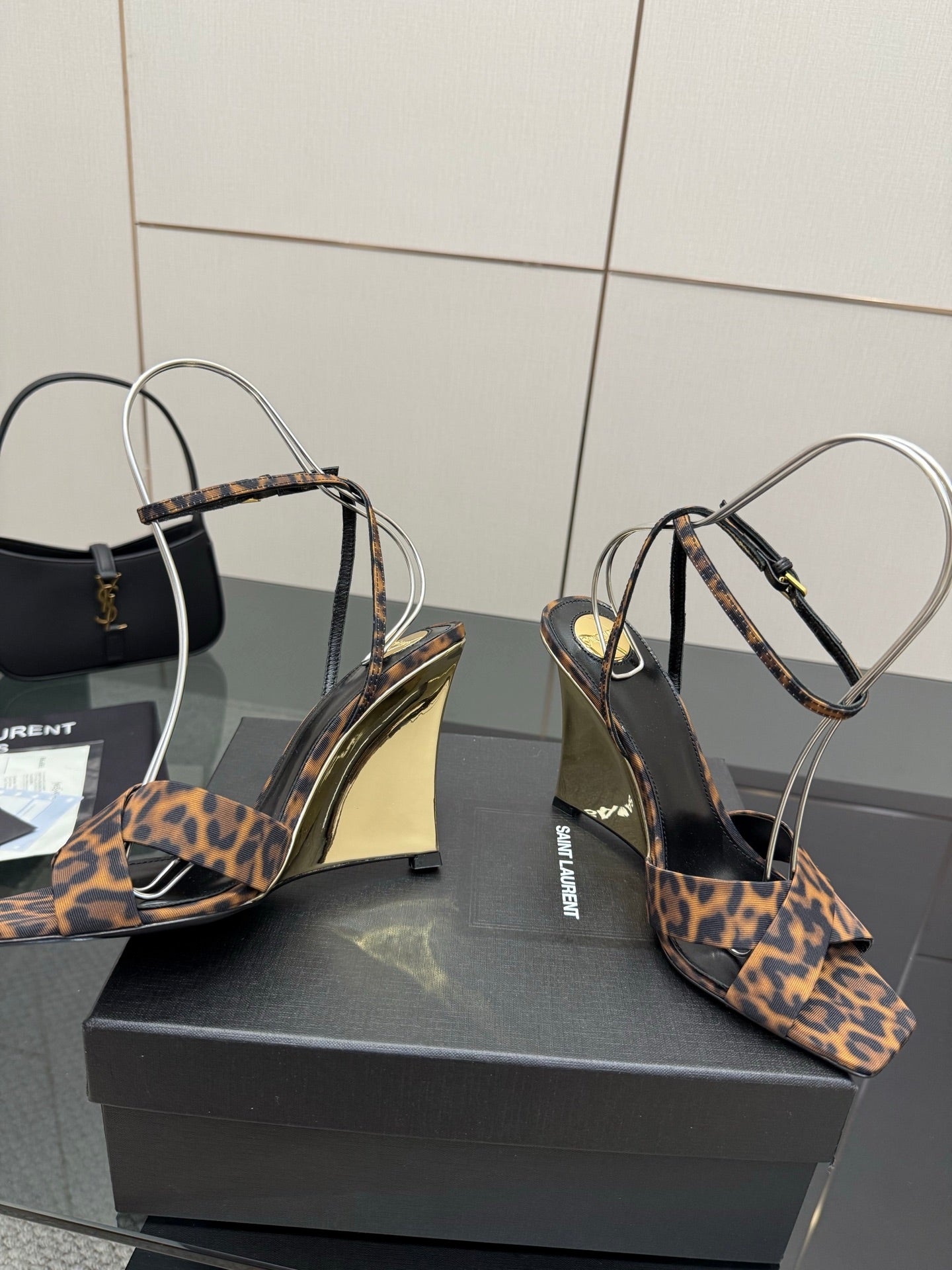 Women's high-heel sandals with leopard-print straps and clear ankle loops, angled view.