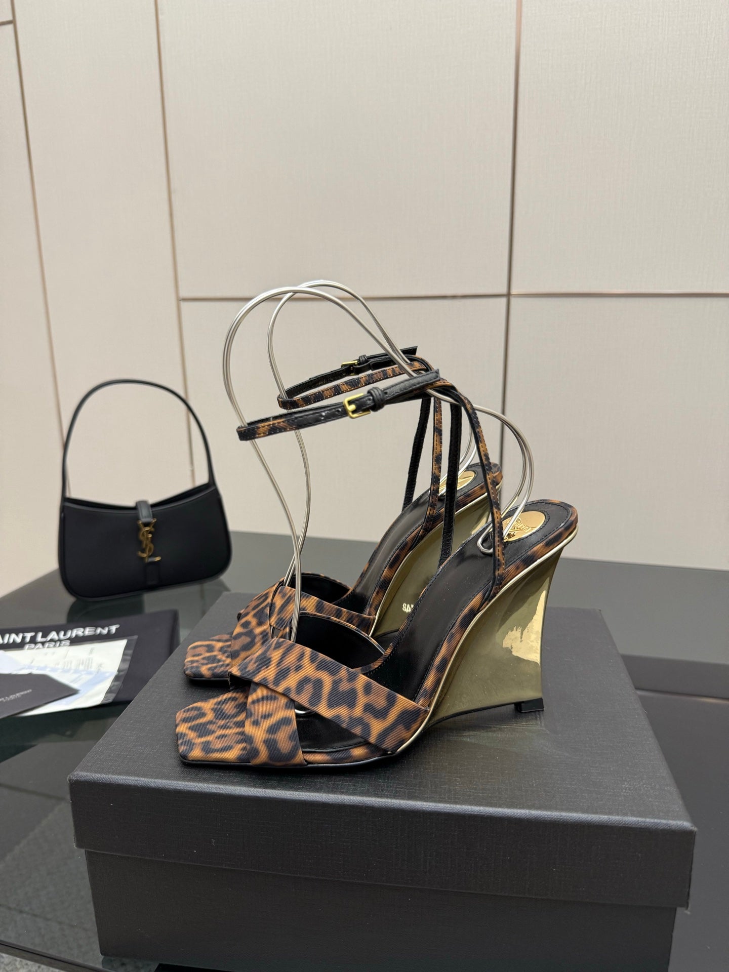 Women's high-heel sandals with leopard-print fabric straps and clear ankle loops, side view.