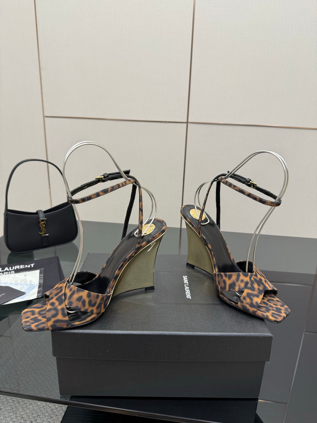 Women's high-heel sandals with leopard-print straps and clear ankle loops, pair on box.