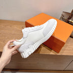 Hermes white unisex sneaker, hand-held side view, lace-up with ribbed sole