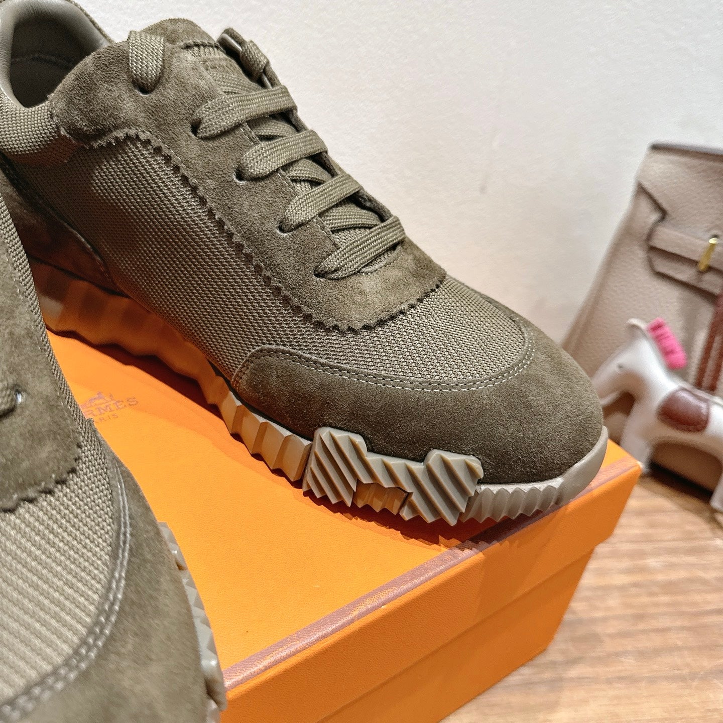 Hermes unisex sneaker close-up: olive canvas upper, lace-up, textured outsole and contrast stitching