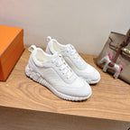 Hermes white unisex sneakers, angled pair, lace-up design with stitched panel details