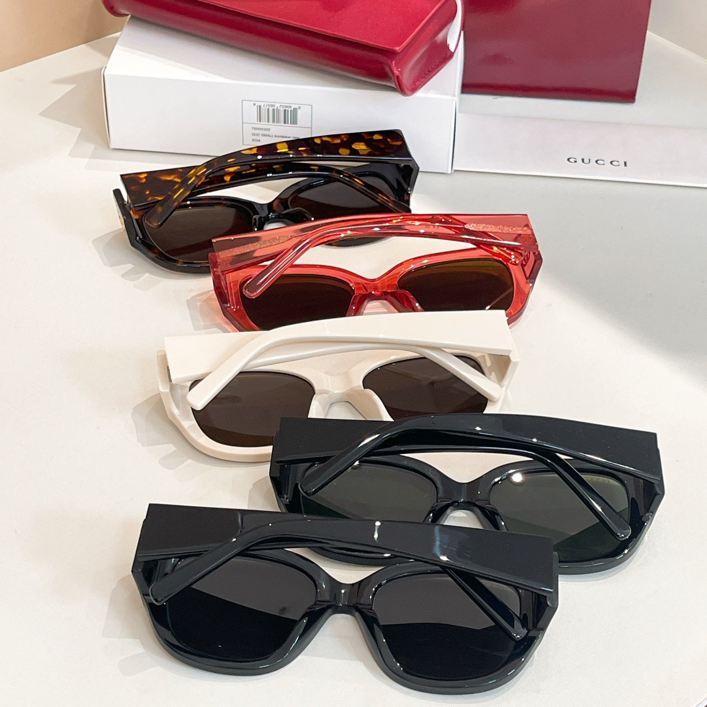 Assorted Gucci sunglasses with tortoiseshell, red, white, and black frames on display.