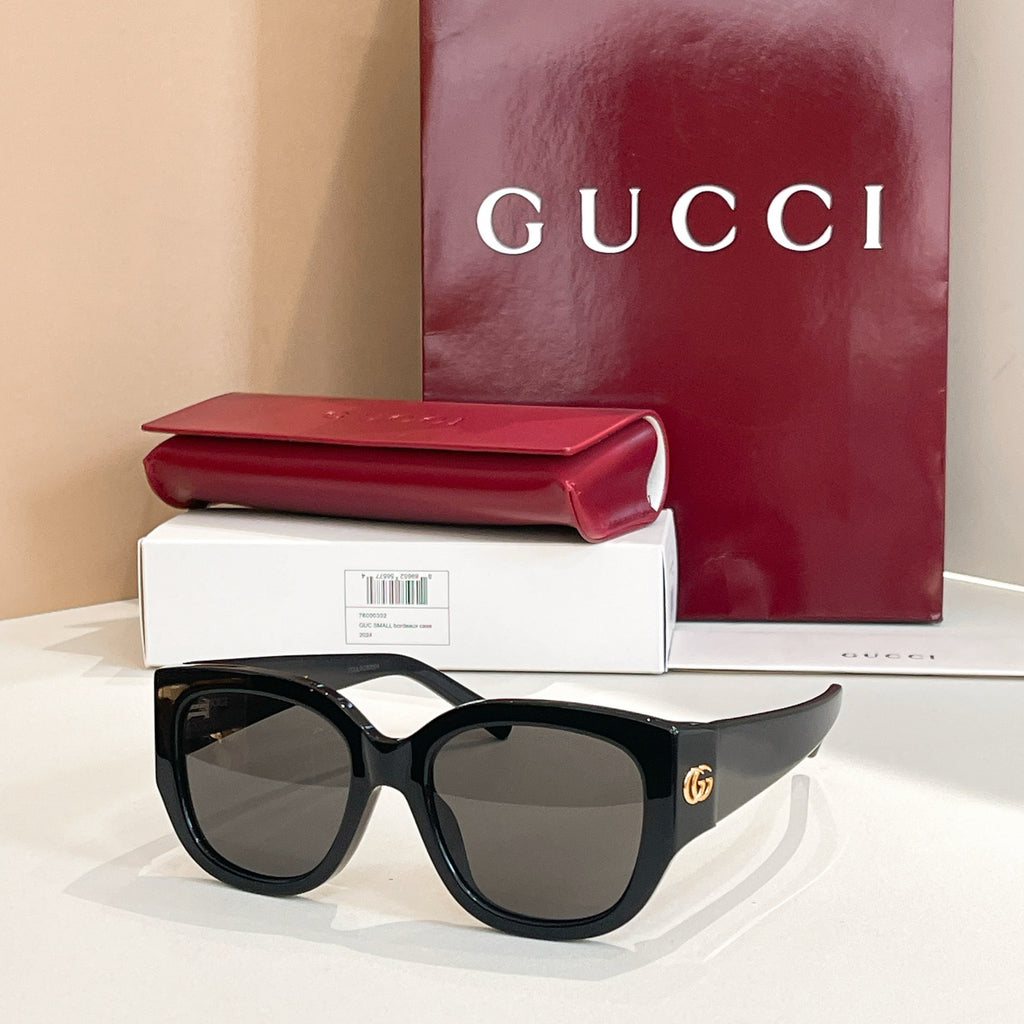 Black Gucci sunglasses with oval lenses and thick acetate frames, gold logo at temple.