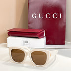White Gucci sunglasses with oval brown lenses and thick acetate frames, gold logo on side.