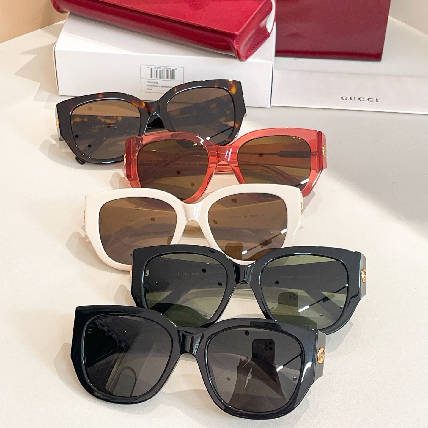 Set of Gucci sunglasses with black, red, and white frames; separate pairs stacked.