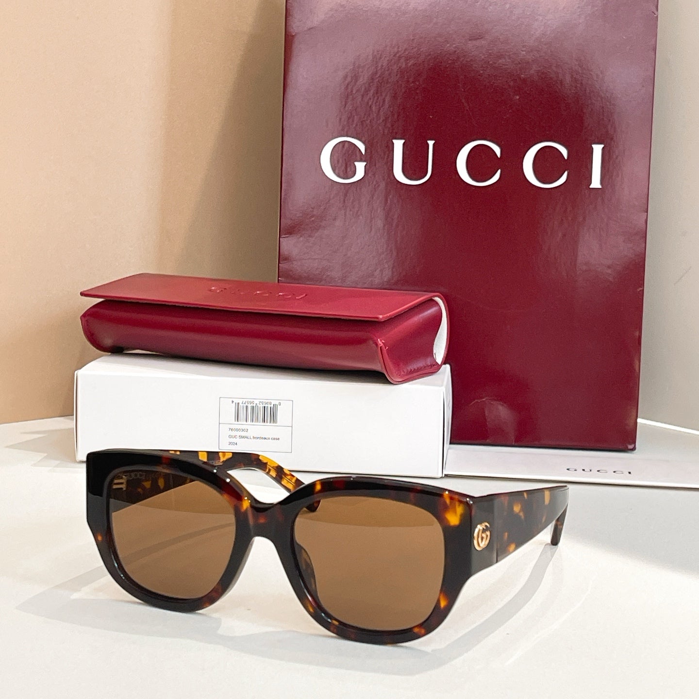 Tortoiseshell Gucci sunglasses with oval amber lenses and thick acetate frames, gold logo detail.