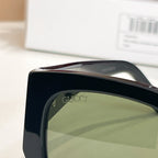 Black Gucci sunglasses temple detail with lens curve and metal hinge.