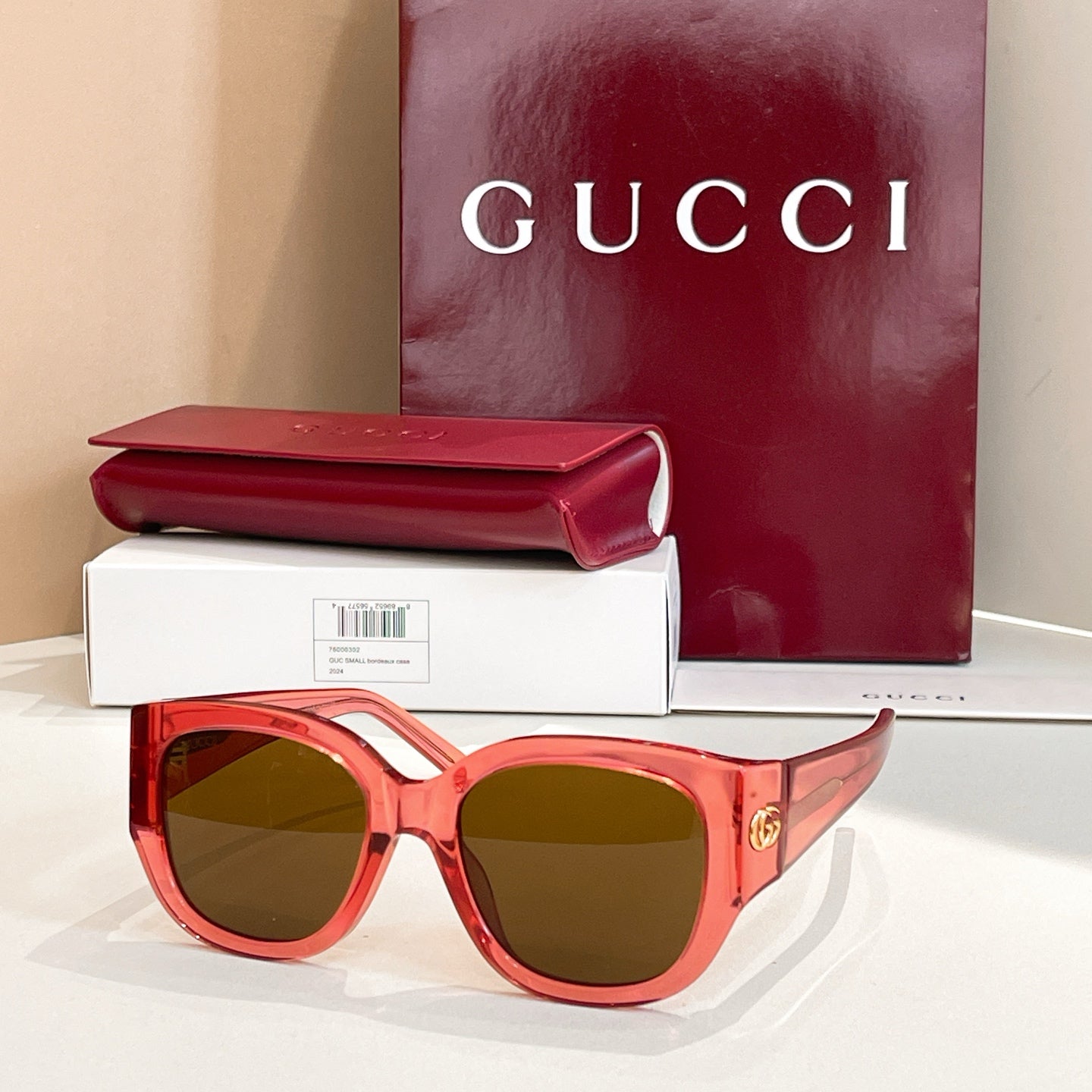 Pink Gucci sunglasses with oval dark lenses and thick acetate frames, gold logo on temple.