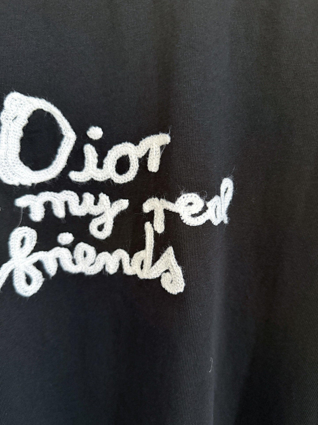 Close-up of white Dior “for my real friends” graphic on black short-sleeve T-shirt
