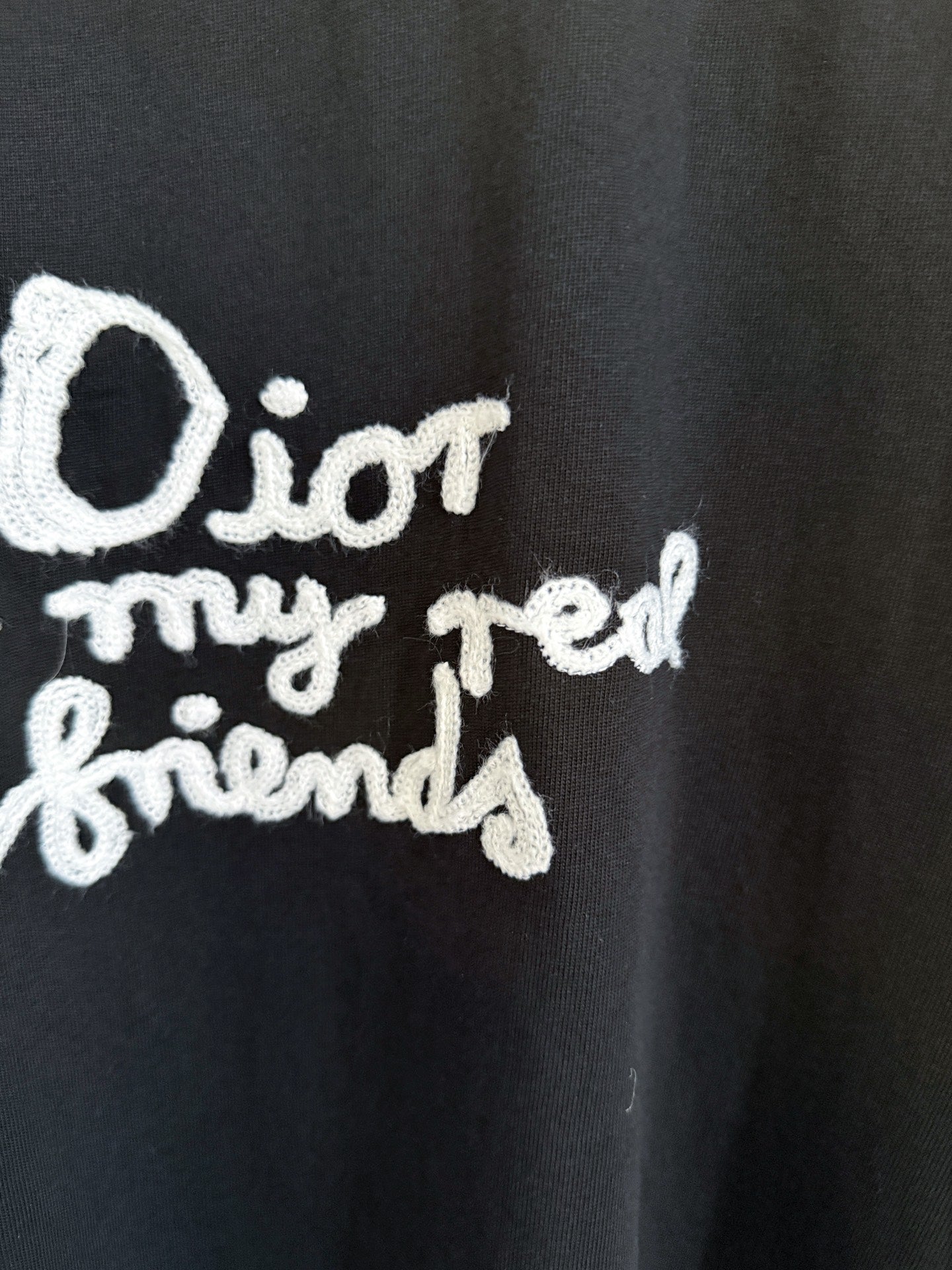 Close-up of white Dior “for my real friends” graphic on black short-sleeve T-shirt