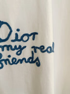 Close-up of blue embroidered text on white short-sleeve Dior T-shirt: “for my real friends”