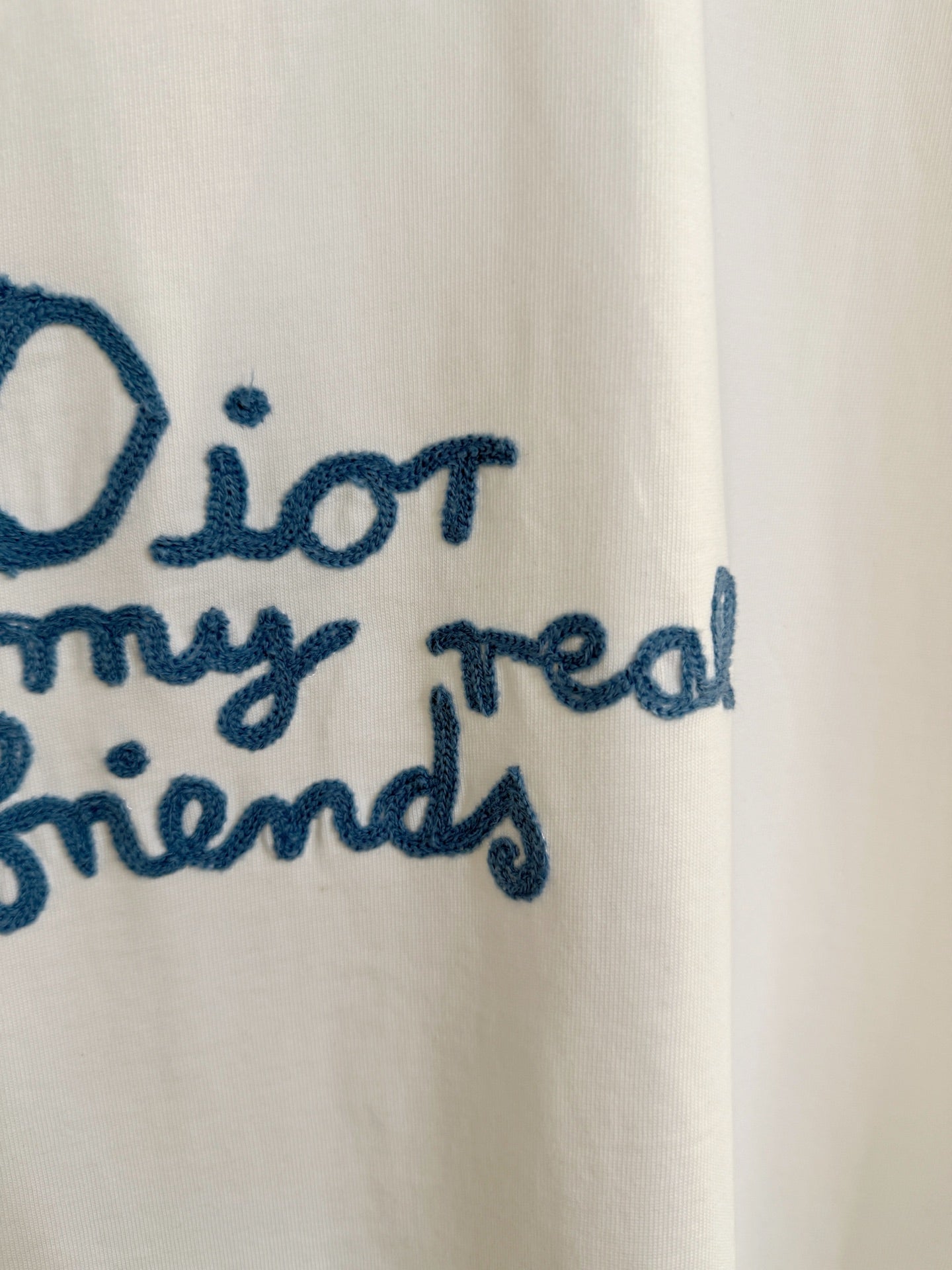 Close-up of blue embroidered text on white short-sleeve Dior T-shirt: “for my real friends”