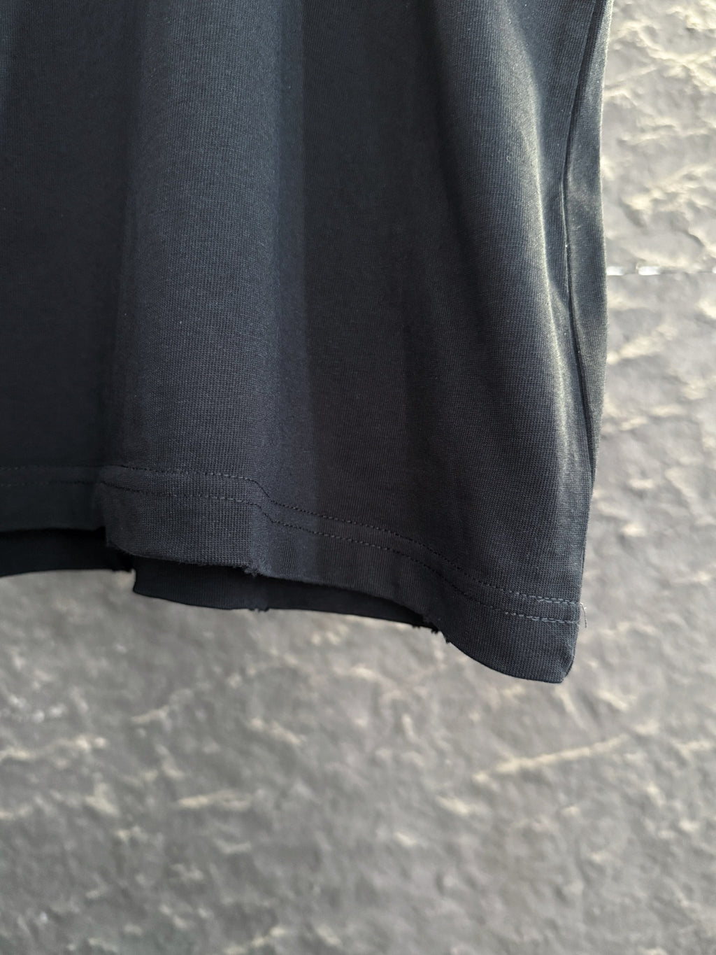 Black short-sleeve T-shirt hem with visible stitching at bottom edge