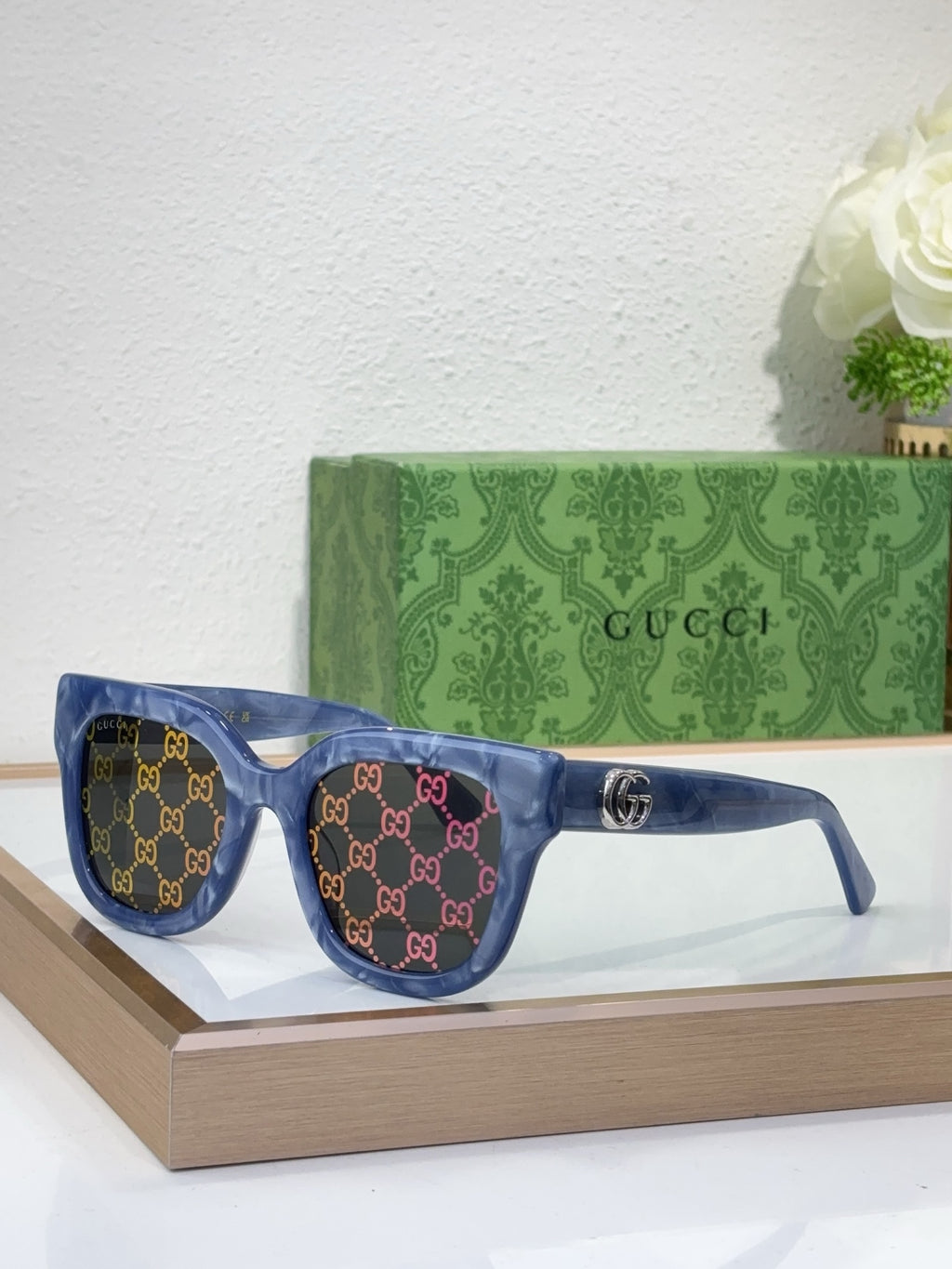 Gucci sunglasses with blue frame, GG pattern, dark lenses, and gold logo emblem