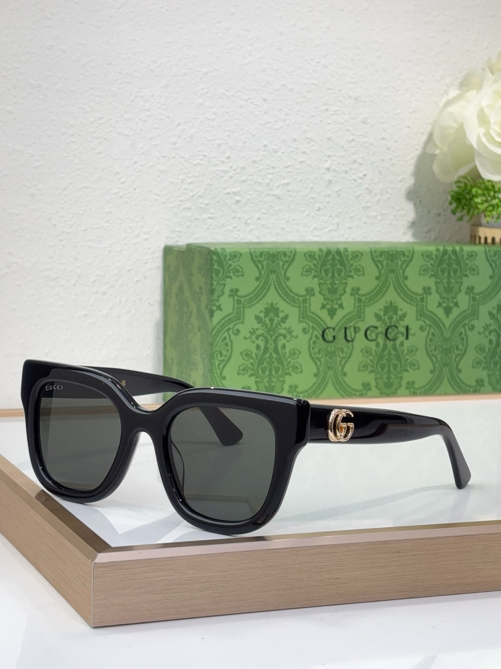 Gucci sunglasses with black frame, dark lenses, and gold logo detail on temple