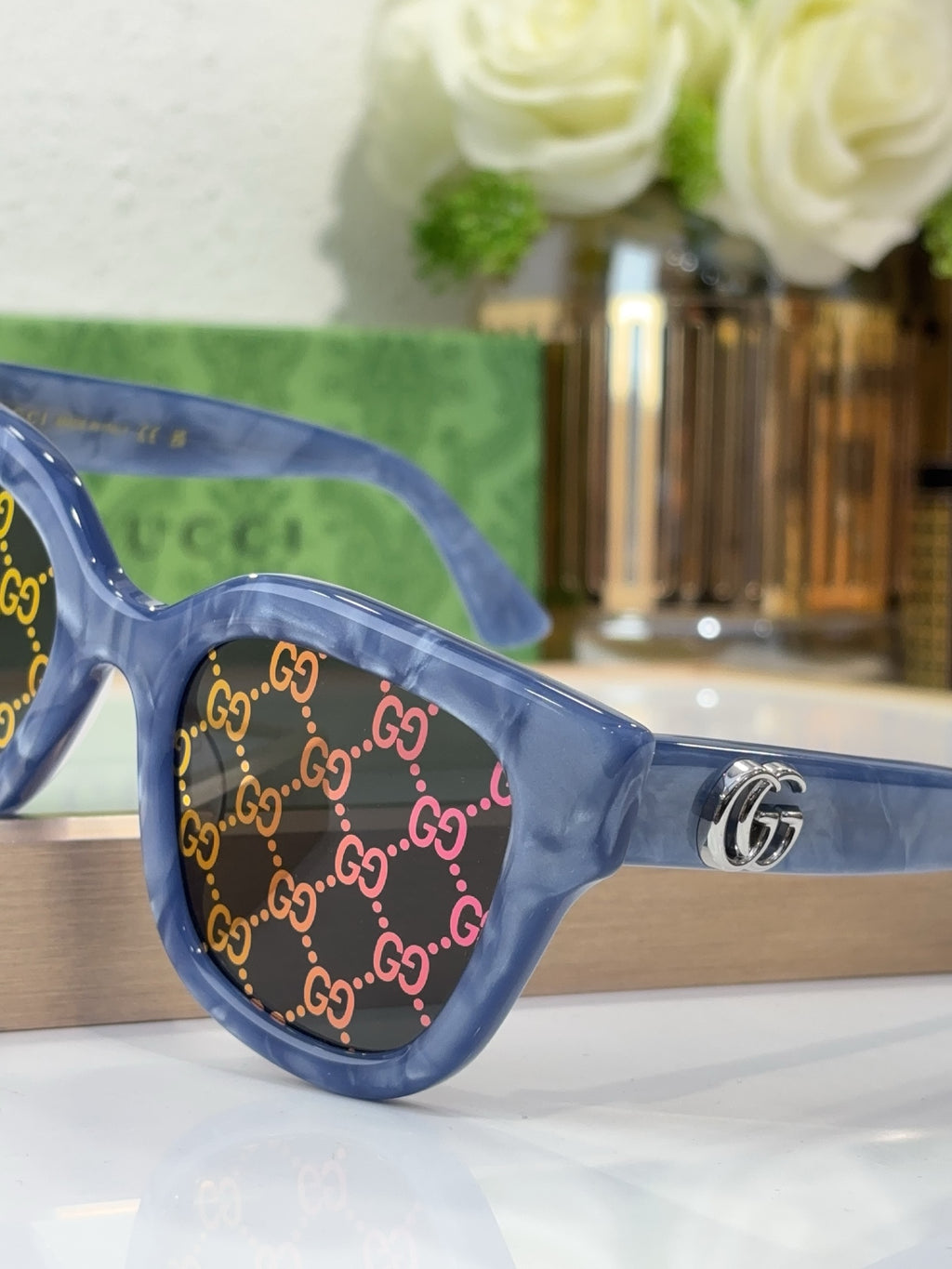 Gucci sunglasses close-up with blue transparent frame, GG monogram, gold logo emblem