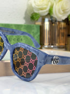 Gucci sunglasses close-up with blue transparent frame, GG monogram, gold logo emblem
