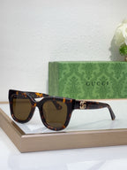 Gucci sunglasses with dark tortoiseshell frame, dark lenses, and gold logo emblem
