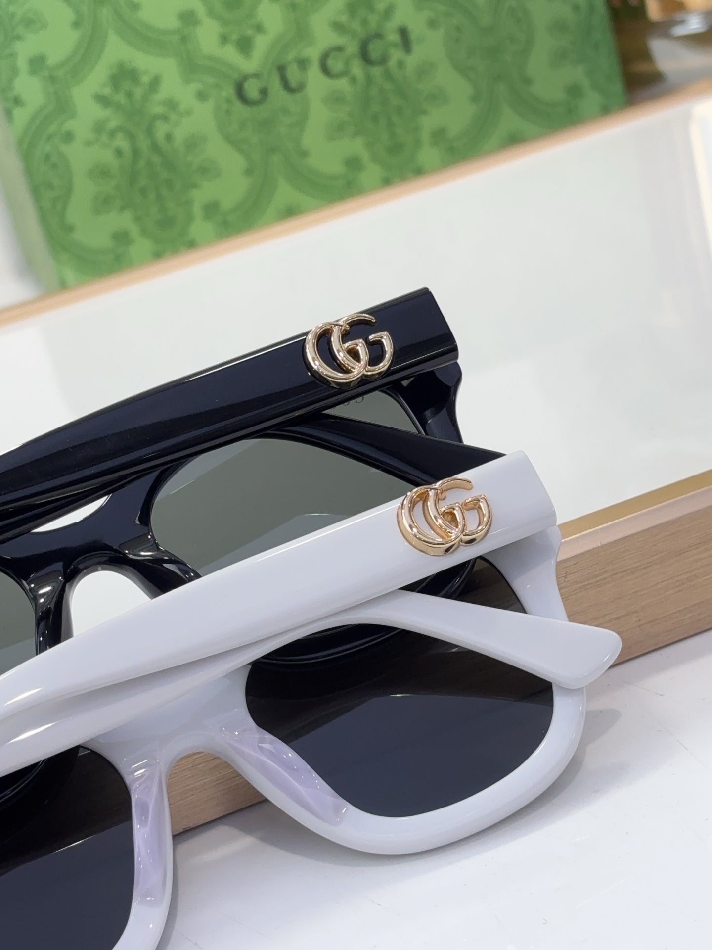 Gucci sunglasses close-up of white and black frames with gold GG logo accents