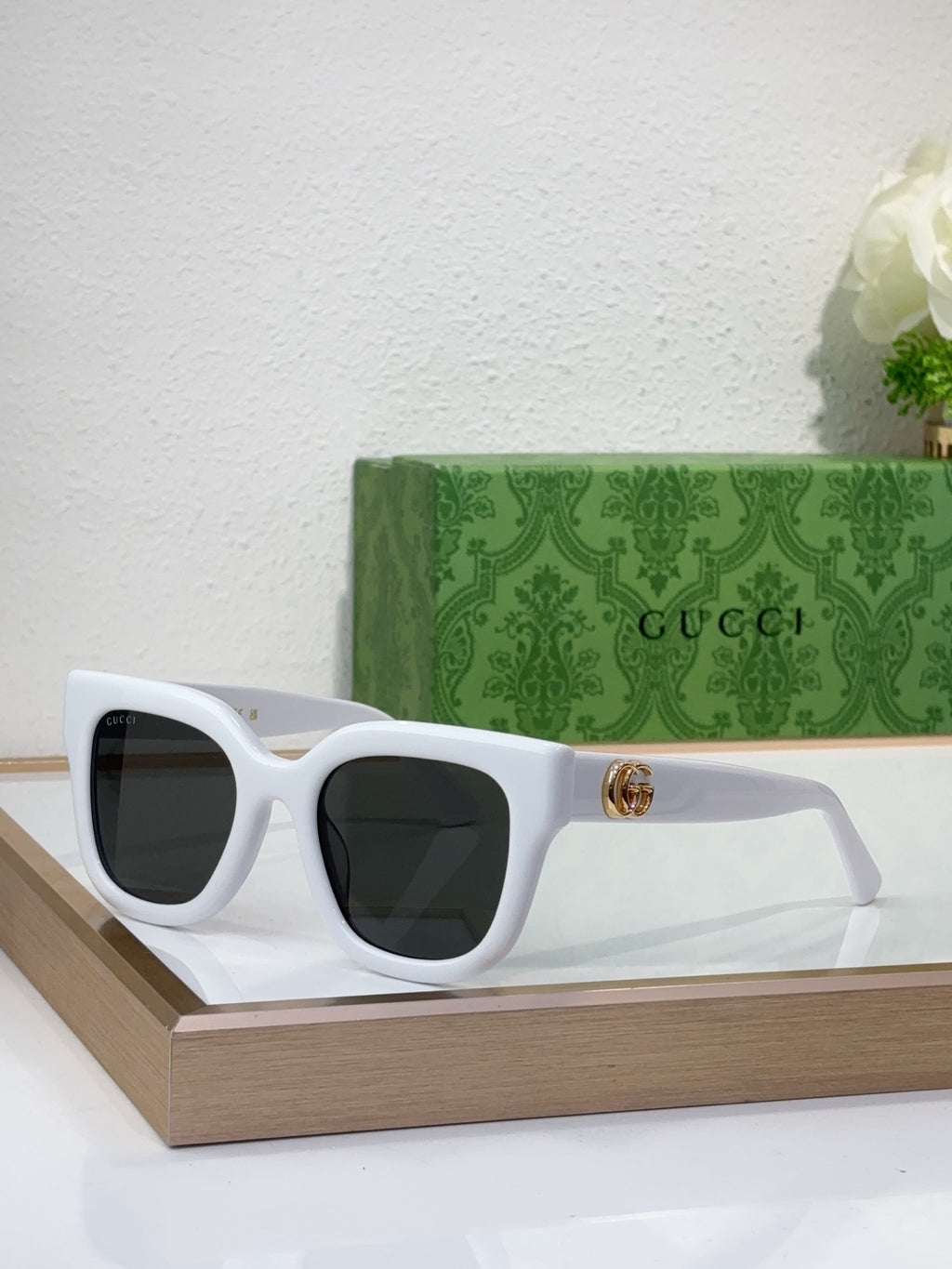 Gucci sunglasses with white frame, dark lenses, and gold logo detail on temple