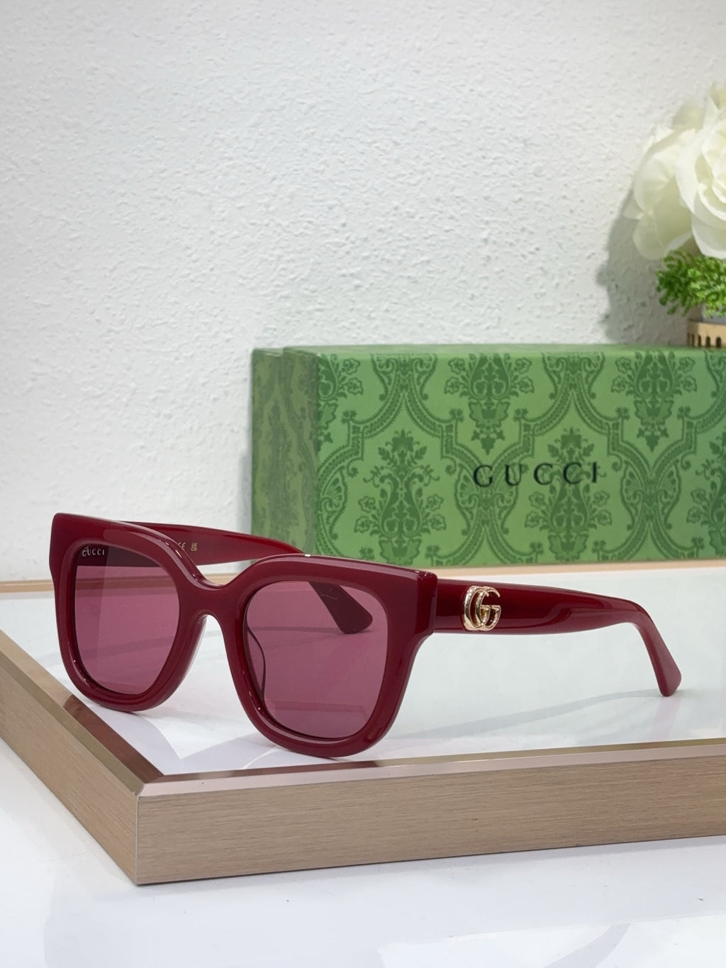 Gucci sunglasses with burgundy frame, dark lenses, and gold logo detail on temple