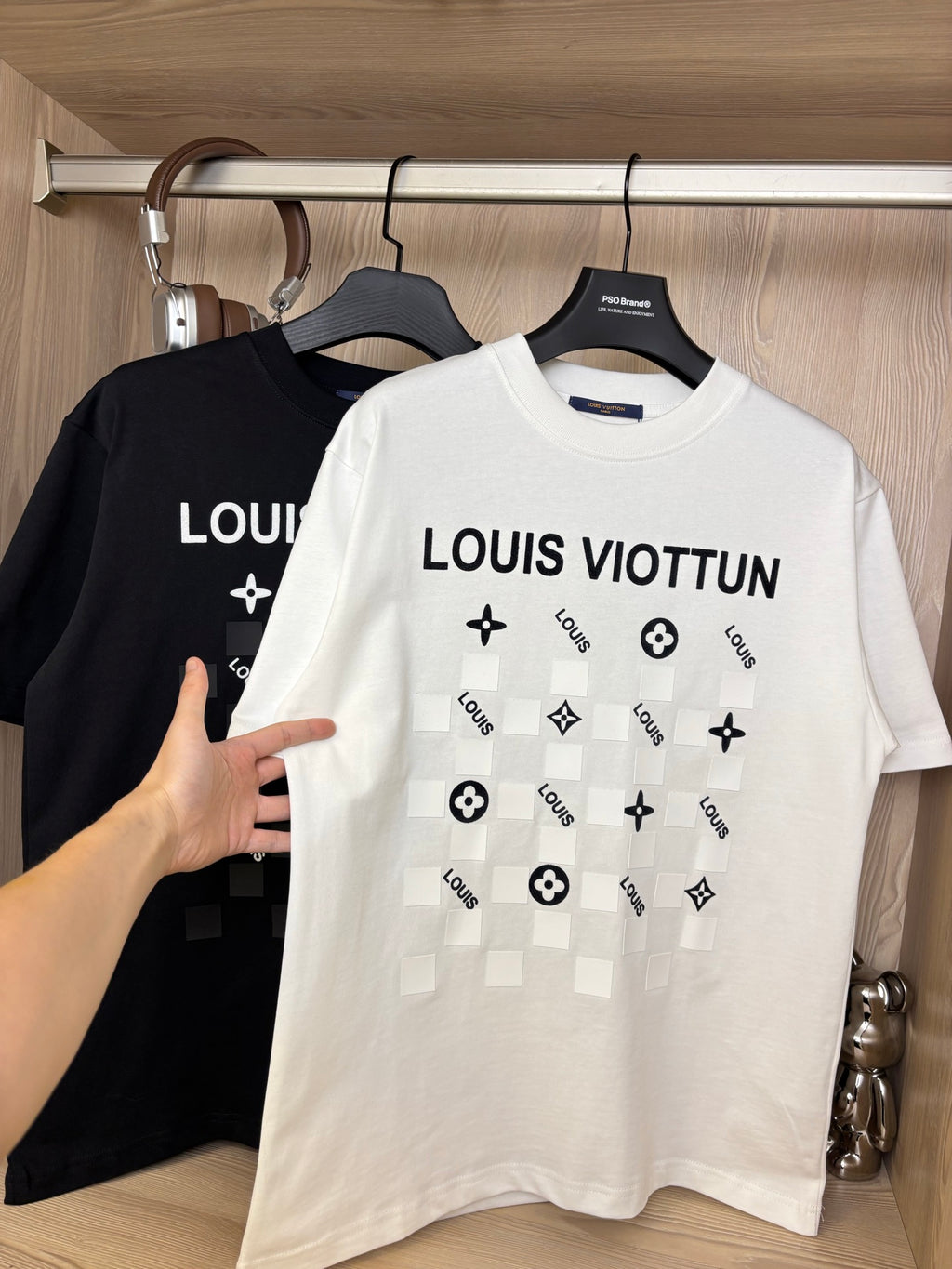 White crewneck T-shirt with “LOUIS VIOTTVN” chest graphic, black shirt behind