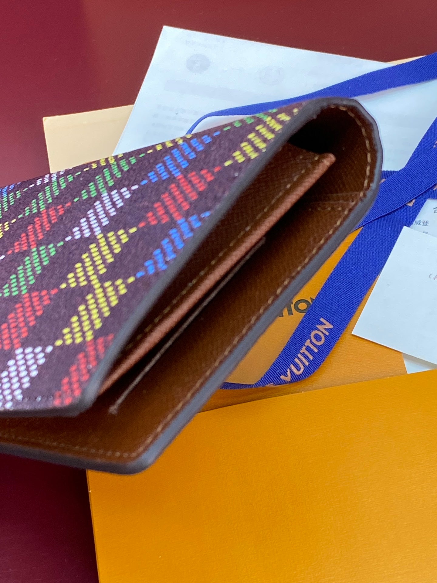 Louis Vuitton multicolor checkered small bag open to reveal brown interior
