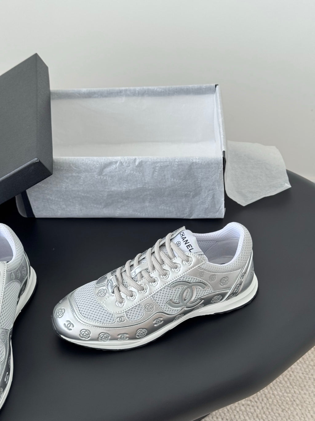Chanel unisex white sneaker with lace-up front and side logo, on display