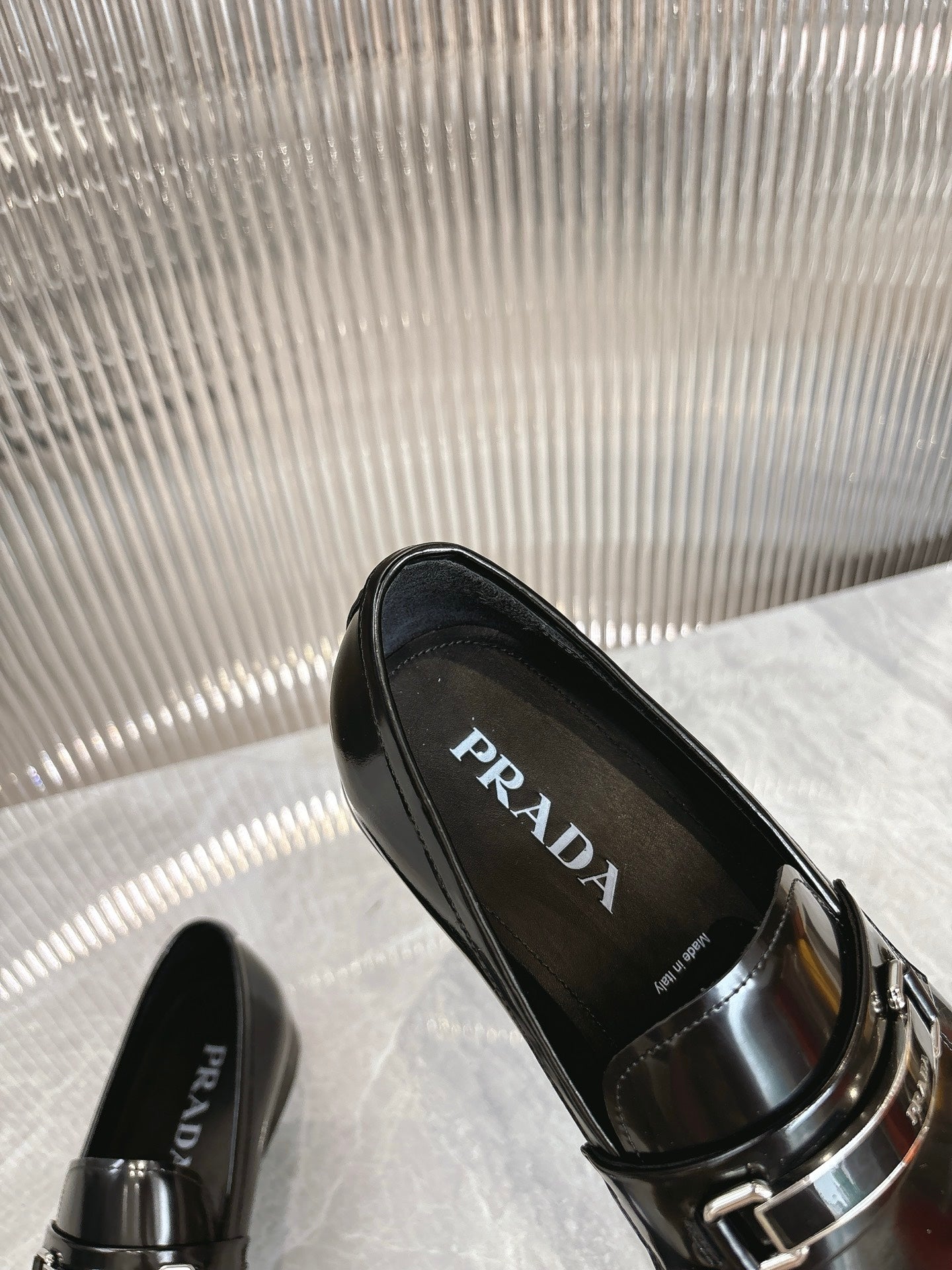 Black patent loafers with silver buckle strap, PRADA logo visible inside