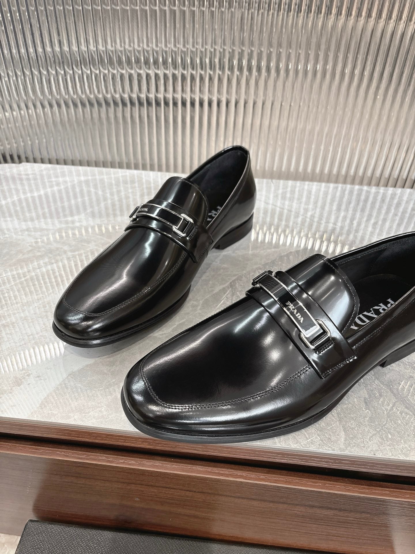Black patent loafers with silver buckle strap and PRADA label on insole