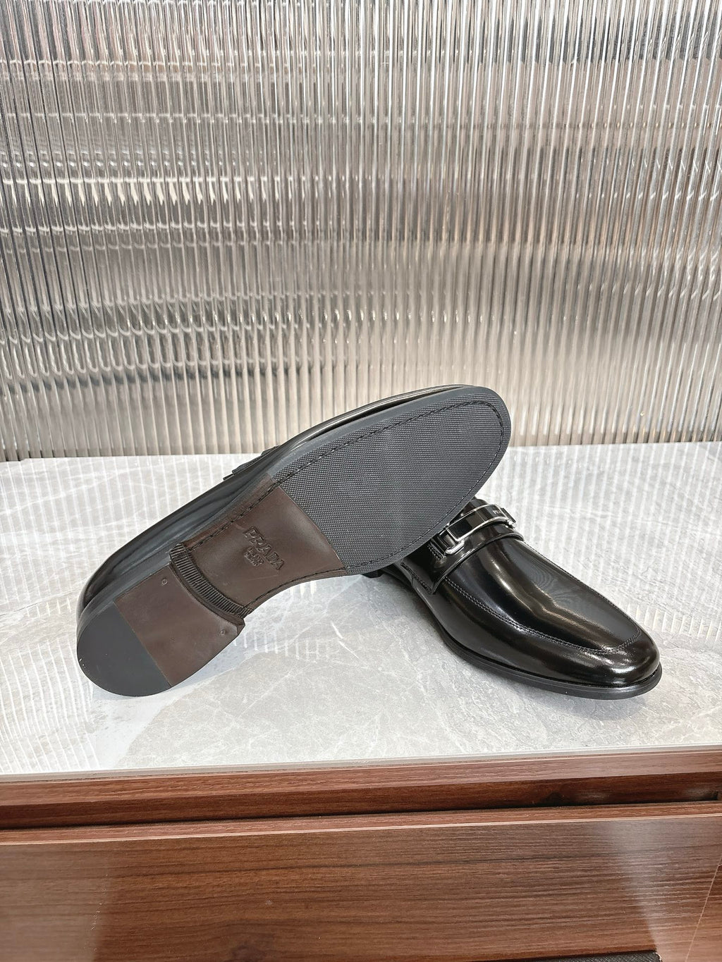 Black patent loafers showing outsole and heel underside, silver buckle strap