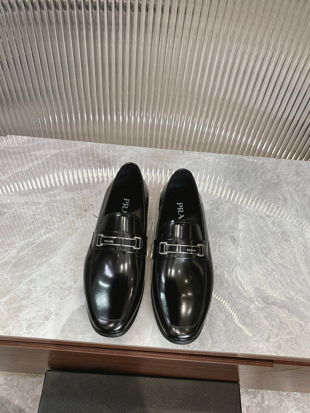 Black patent leather loafers with silver buckle straps, pair on display
