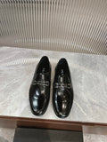 Black patent leather loafers with silver buckle straps, pair on display