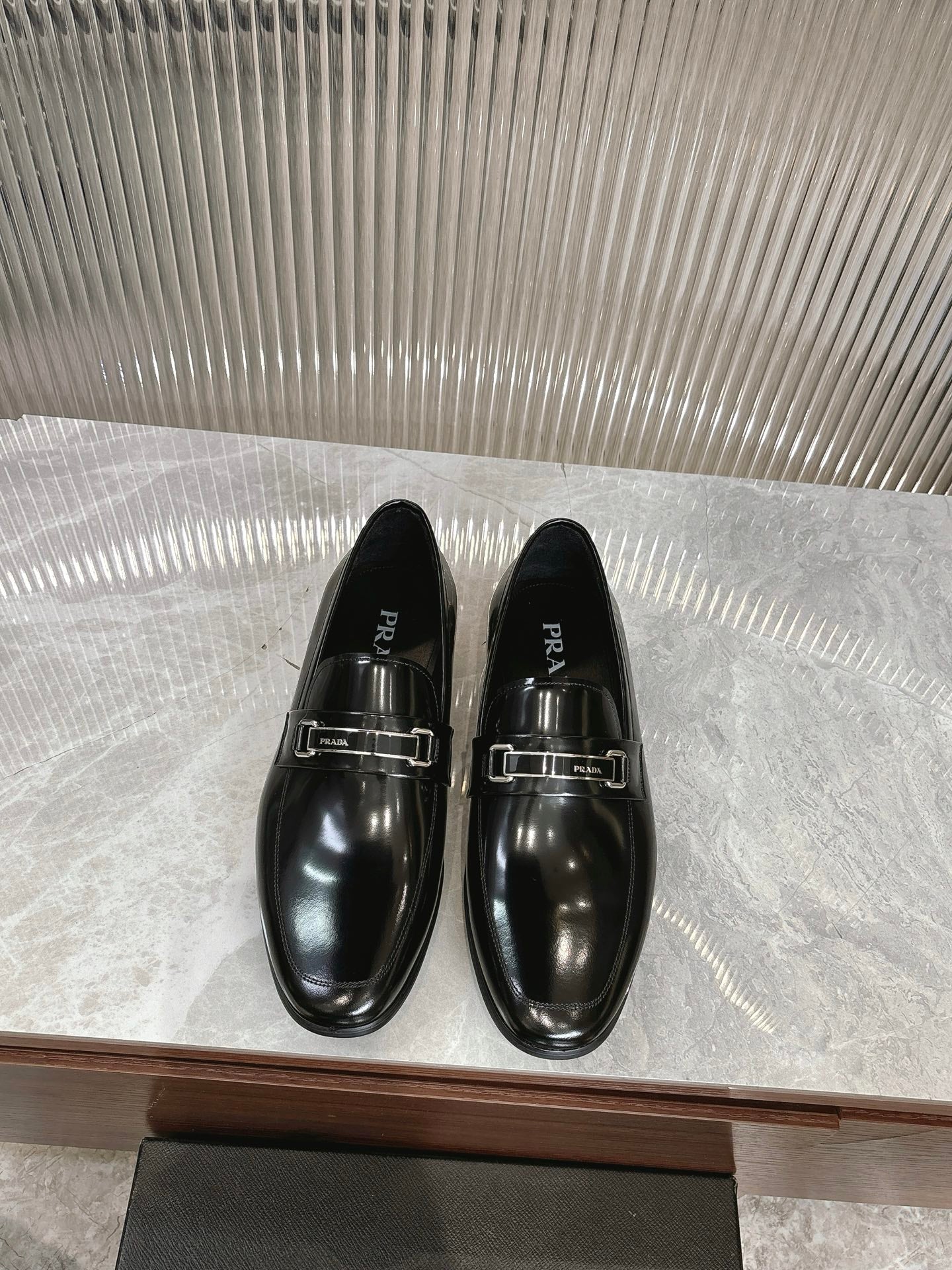 Black patent leather loafers with silver buckle straps, pair on display