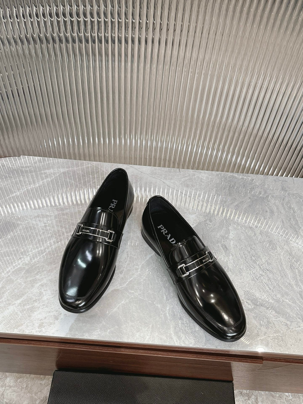 Black patent leather loafers with silver buckle detail, two shoes angled