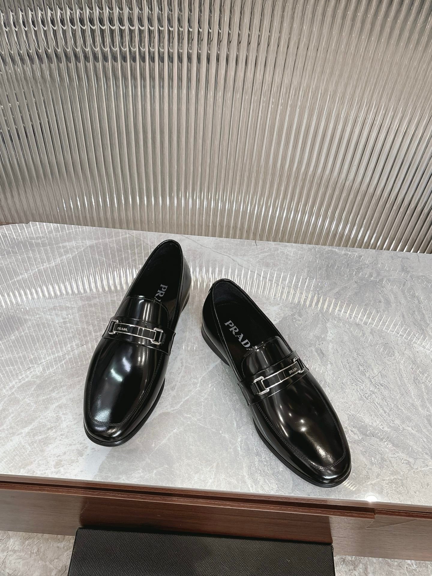 Black patent leather loafers with silver buckle detail, two shoes angled