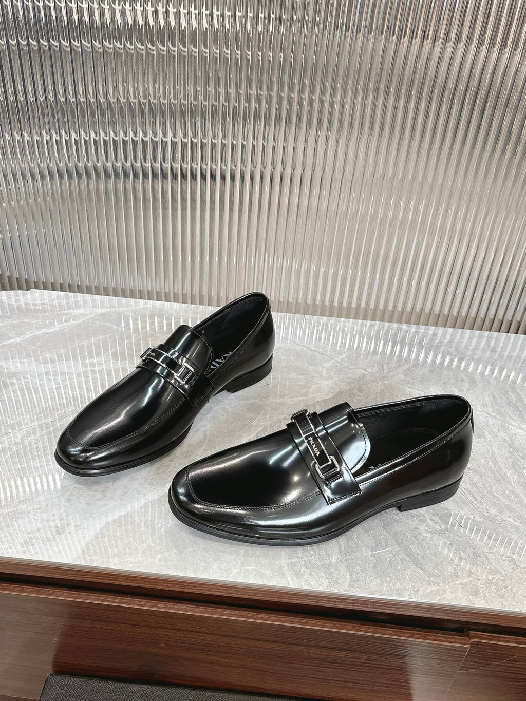 Black patent loafers with double strap silver buckle, pair on display