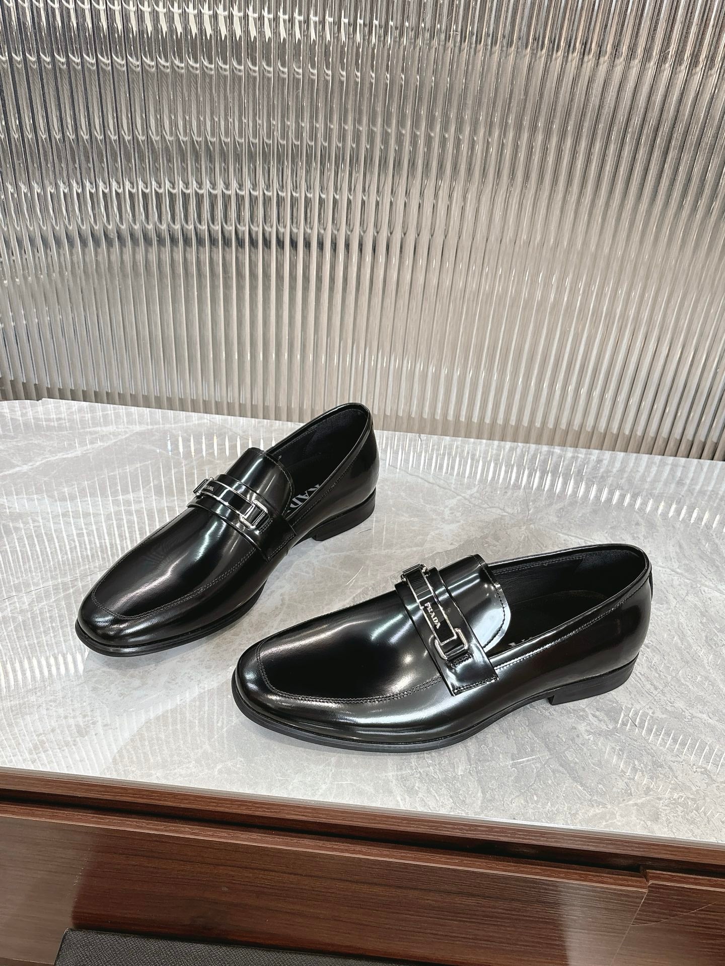 Black patent loafers with double strap silver buckle, pair on display