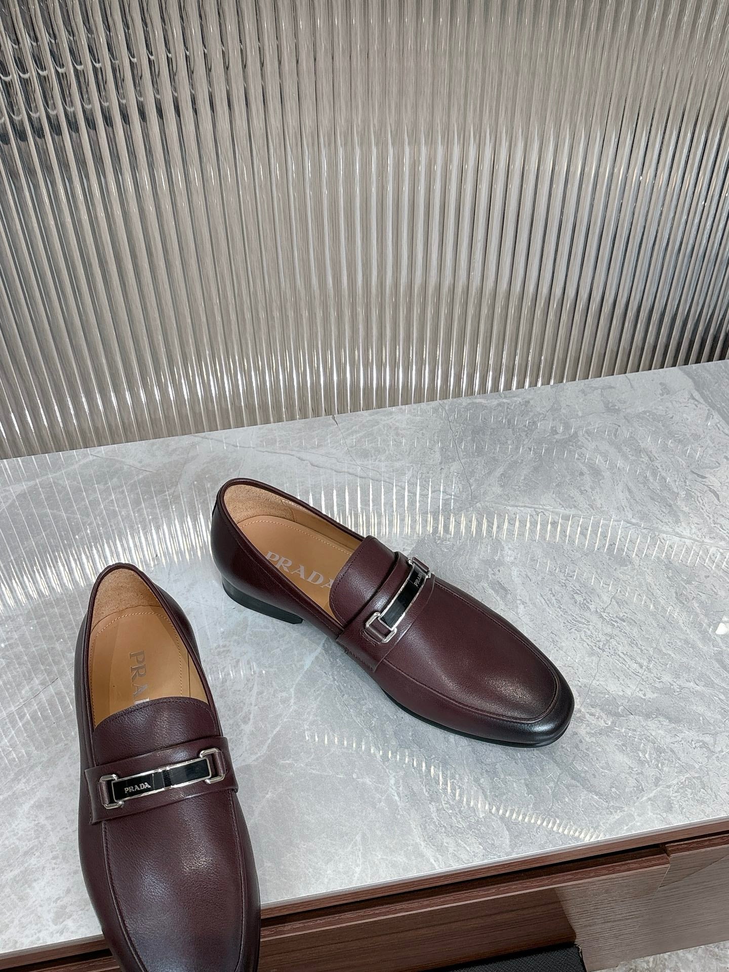 Prada unisex leather loafers, angled top view, dark burgundy metal buckle