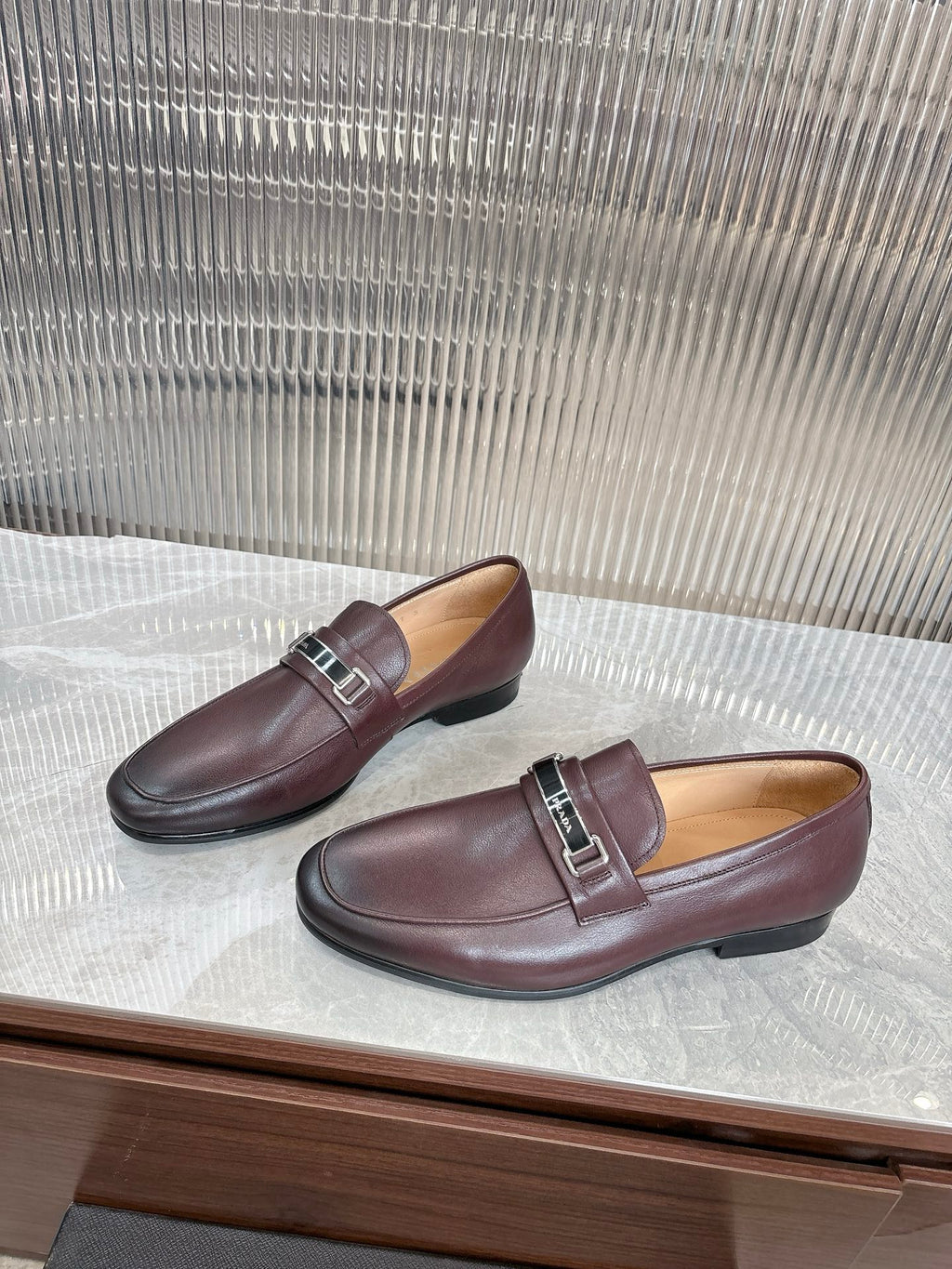 Prada unisex leather loafers, pair on shelf, dark burgundy buckle detail