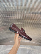 Prada unisex leather loafer, hand holding, dark burgundy slip-on with buckle