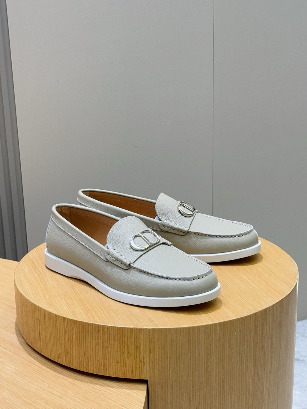 Light beige leather loafers with silver-tone D buckle on the vamp