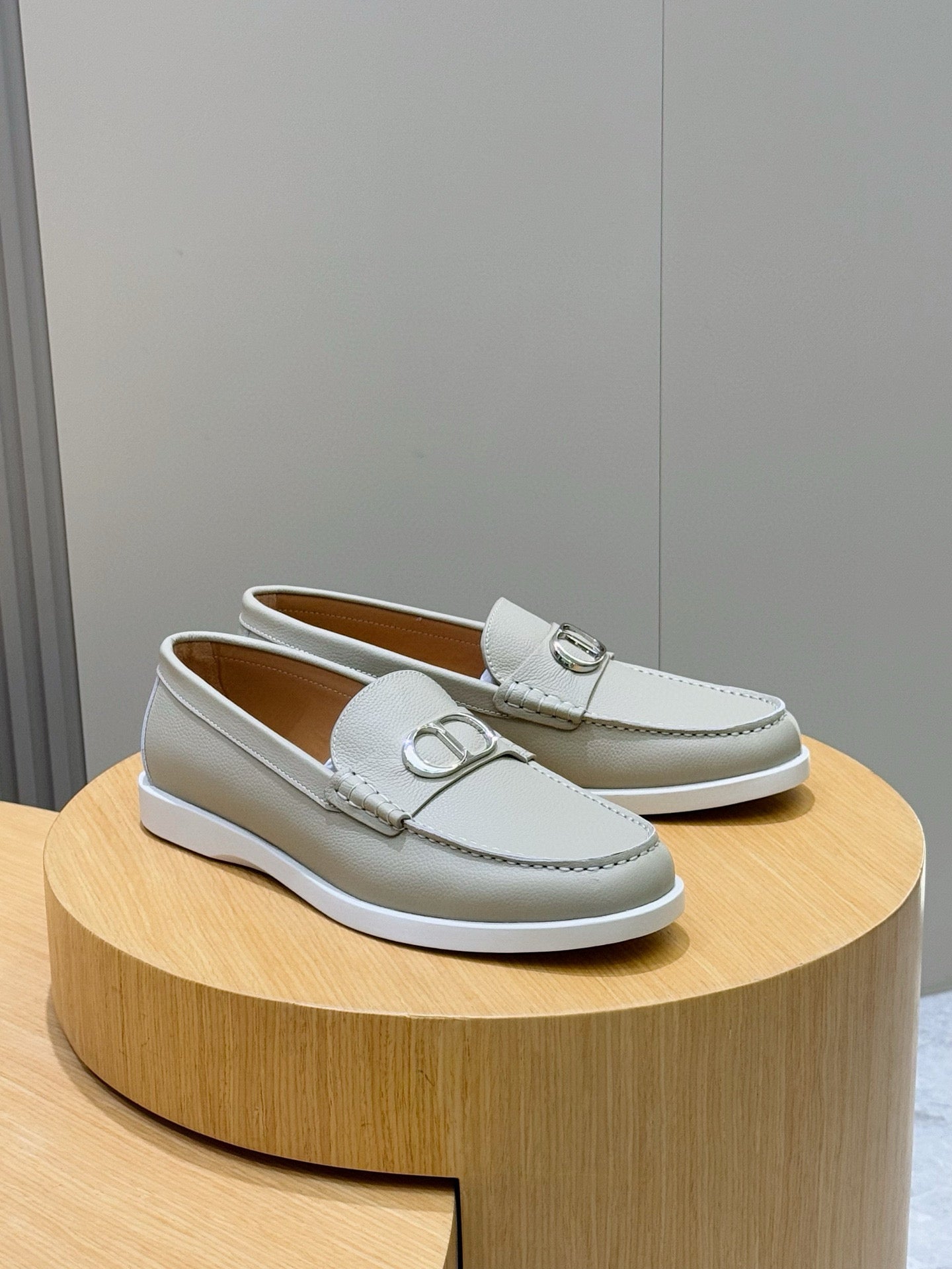 Light beige leather loafers with silver-tone D buckle on the vamp